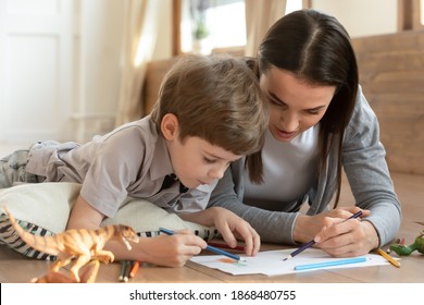 Caring young Caucasian mother   small son drawing painting in album at home together  Loving mom nanny have fun learn play and little boy child  lying floor in living room relaxing weekend