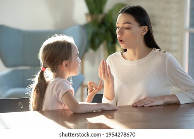 Caring young Caucasian mother teach small 7s daughter articulation exercised at lesson at home. Mom or teacher and little girl child learn pronouncing sounds together. Pronunciation concept. - Shutterstock ID 1954278670