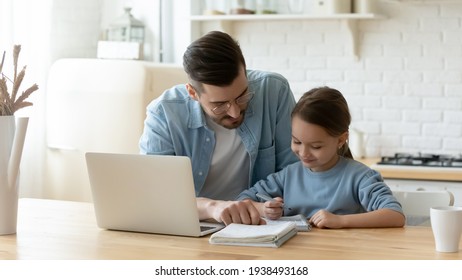 Caring young dad helping small primary pupil kid daughter preparing school homework, sitting together at table. Happy little child girl involved in doing task, studying homeschooling with father. - Shutterstock ID 1938493168