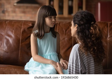 Caring Young Hispanic Mother Hold Little Daughter Hands Talk Make Peace After Family Fight Or Misunderstanding. Loving Latino Mom Comfort Caress Unhappy Small Girl Child Or Reconcile.