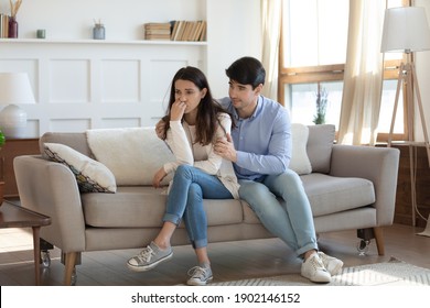 Caring young man hugging woman from back, comforting, apologizing, frustrated wife feeling depressed, thinking about relationship problems, loving husband asking forgiveness after quarrel, conflict