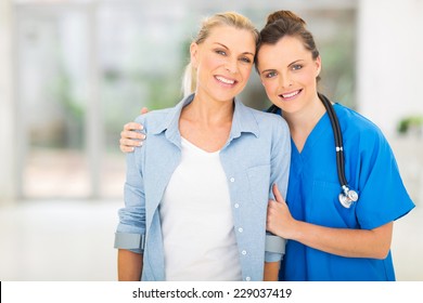 Caring Young Nurse Standing With Disabled Patient In Office