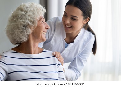 Caring Young Nurse Support Assist Positive Old Lady Patient At Home Or Hospital, Smiling Female Caregiver Or Doctor Give Help To Optimistic Mature Senior Grandmother, Elderly Healthcare Concept