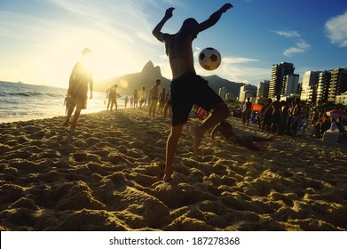Carioca Brazilians playing altinho futebol beach football kicking soccer balls at sunset Ipanema Beach Rio de Janeiro