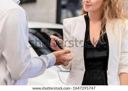 Carkey Over Handing. Close up of young smiling woman Hand over keys to customers businessman of a new car. The concept for key car rental