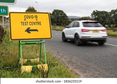 Carlisle / Great Britain - September 26, 2020 : Yellow Covid 19 Test Centre Road Sign At The Side Of Highway With Direction Arrow To Entrance.