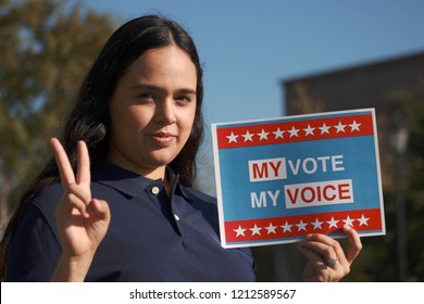 Carlsbad, CA / USA - October 25, 2018: Young Hispanic woman holding a sign "My Vote My Voice"  to encourage Latino vote
