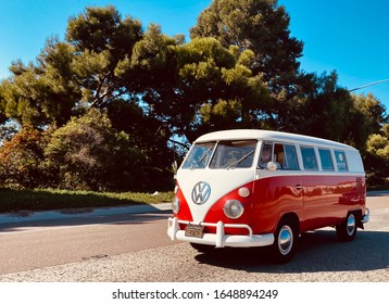 Carlsbad, California / USA - October 28, 2019: Red & white split-window Volkswagen Bus driving down California highway