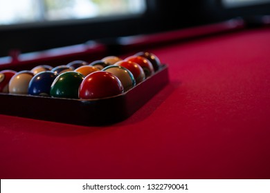 Carlsbad, California/United States - 07/23/18: A Dimly Lit Billiards Table, With Red Felt, Racked Pool Balls, At An Angle With A Window In The Background.