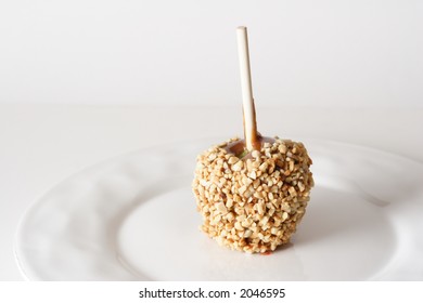 Carmel Apple With Nuts On A White Plate And White Background.