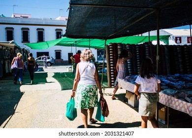 Carmona, Spain August 9, 2021 An Elderly Woman And A Child Back Turned Walking And Unidentified People In The Background All Wearing Masks In Mandatory In A Local Market Set Up Every Monday