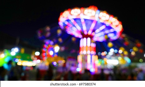 Carnival Amusement Park Ride With Swings. Spinning Fair Ride At Night With Bright Purple Red And Yellow Lights.