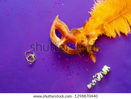 Carnival mask on purple background with sparkles. Festive backdrop for projects. Flat lay, close up. Top view, copy space.