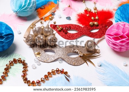 Carnival masks, paper balls and feathers on white background