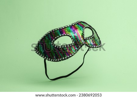 Carnival masquerade mask flying in antigravity on green background with shadow. Levitation object in the air. Creative minimal layout