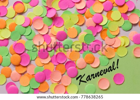 Carnival party background concept, space for text. Written the words in german: Karneval! Colorful confetti spread over table. Warm colors: pink, yellow and orange.