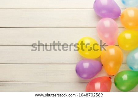 Carnival or party border of colorful balloons, top view. Holiday decoration on rustic wood planks with copy space for greeting, invitation or advertising. Birthday background