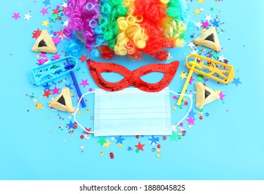 carnival, party and Purim celebration (jewish carnival holiday) over blue background. Coronavirus prevention concept, medical mask