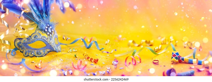Carnival Party - Venetian Mask On Yellow Satin With Shiny Streamers On Abstract Defocused Bokeh Lights - Shutterstock ID 2256242469