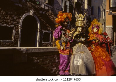 Carnival revelers wearing colorful and sophisticated costumes with masks in an alley at the Carnival of Venice. The historic and amazing marine city full of canals and palaces in northern Italy. - Shutterstock ID 1112949653