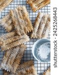 Carnival season.Homemade traditional Italian carnival sweets: chiacchiere sprinkled with icing sugar on white background. Copy space. Overhead view.