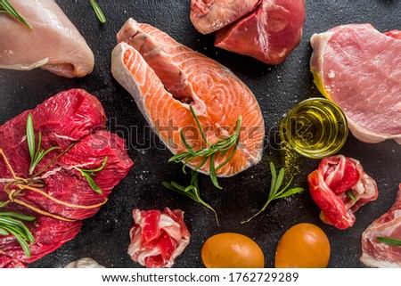 Carnivore diet background. Non vegan protein sources, Different meat food - chicken breast, pork steak, beef tenderloin, eggs, spices for cooking. Black stone concrete background copy space