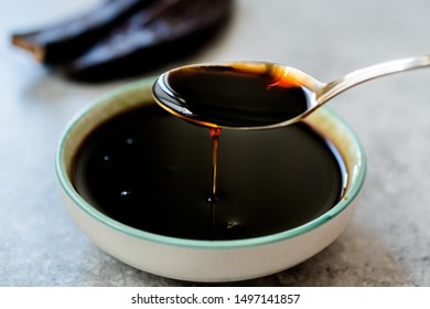 Carob Molasses Dripping From Spoon. Organic Food.