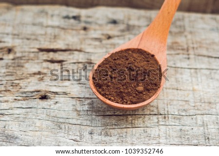 Carob powder in a wooden spoon on an old wooden background
