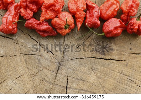 Carolina reaper extreme hot peppers on a wooden background arranged at the top with space for content on bottom.