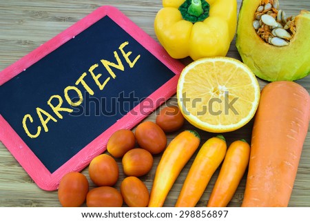 Carotene written on chalkboard with orange color fruits and vegetables