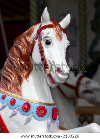 carousel horse, sharp and bright, with a darker, blurred background of another carousel horse