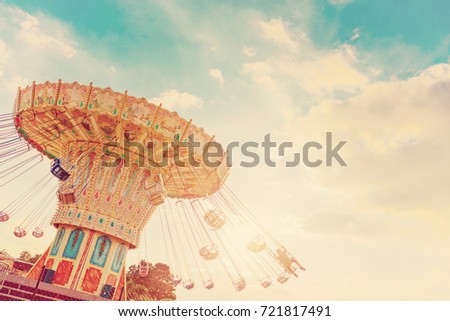 carousel ride spins fast in the air at sunset - vintage filter effects - a swinging carousel fair ride in amusement park at dusk