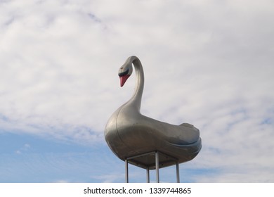 Carousel with swans in the summer amusement park. Swan on the blue cloudy sky background.