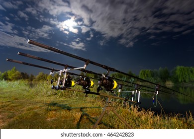 Carp Spinning Reel Angling Rods On Pod Standing.
Night Fishing, Carp Rods, Cloudscape Full Moon Over Lake.
