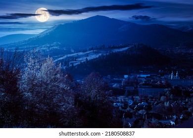 Carpathian Rural Landscape In Autumn At Night. Village In The Valley At The Foot Of The Mountain. Beautiful Countryside Scenery In Full Moon Light. Trees In Fall Foliage On The Grassy Hills