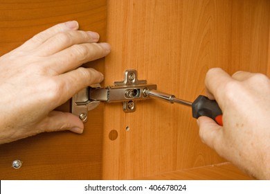 Carpenter Adjusting A Cabinet Door Hinge