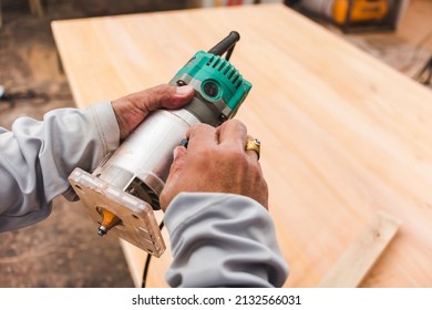 A Carpenter Adjusts Or Checks A Wood Trimmer Compact Wood Palm Router Tool. At A Furniture Making Workshop.