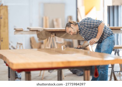 Carpenter applying protective varnish coating to a custom-made wooden table top