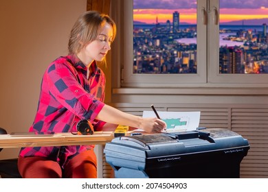 Carpenter With Architectural Drawings. Furniture Company Designer. Furniture Making Process. Woman Carpenter With Pencil. Girl Draws Construction Drawings. Woman Furniture Maker Sitting By Window