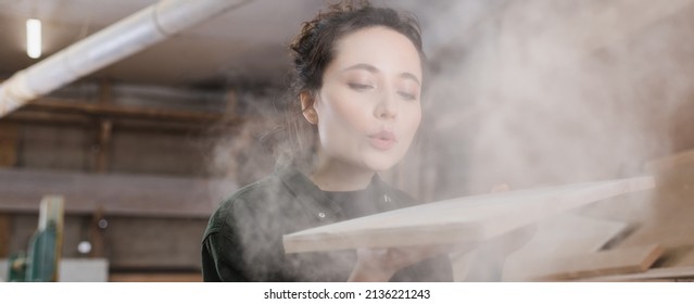 Carpenter blowing sawdust from wooden plank, banner - Powered by Shutterstock