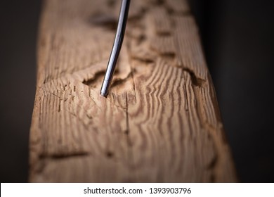 Carpenter Blows Sawdust Out Of Woodworm Marks On Reclaimed Oak Wood Beam