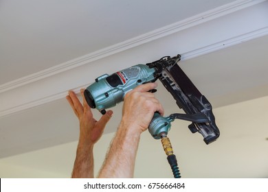 Carpenter Brad Using Nail Gun To Crown Moulding Framing Trim, With The Warning Label That All Power Tools Have On Them Shown Illustrating Safety Concept