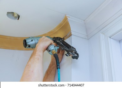 Carpenter Brad Using Nail Gun To Crown Moulding Framing Trim, With The Warning Label That All Power Tools Have On Them Shown Illustrating Safety Concept