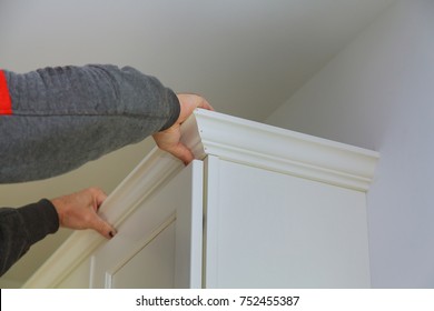 Carpenter Brad Using Nail Gun To Crown Moulding On Kitchen Cabinets Framing Trim, With The Warning Label That All Power Tools Have On Them Shown Illustrating Safety Concept