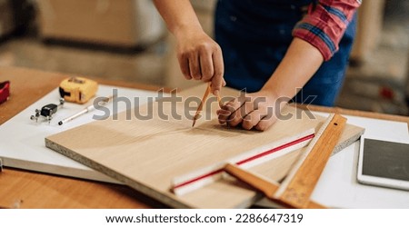 A Carpenter carefully measures, marks dimensions, and lays out reference lines on wood using scribe, divider, square, ruler, and caliper. The woodworking process need skills, experience, precision.