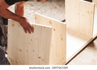 Carpenter is carefully putting together pieces of wood, creating a piece of furniture in his workshop. The image highlights the precision and craftsmanship involved in woodworking - Powered by Shutterstock