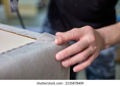 Carpenter checks the quality of the upholstery of the upholstered furniture frame. Inspection and quality control of the work performed. Master registrar in furniture production.