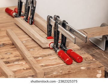 Carpenter clamps are fixed to boards. Gluing joinery in the workshop