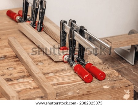 Carpenter clamps are fixed to boards. Gluing joinery in the workshop