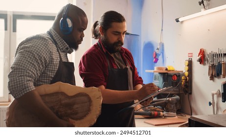 Carpenter and colleague looking over technical schematics, brainstorming ideas for wooden object. Master and apprentice analyzing blueprints to execute furniture assembling project, camera B - Powered by Shutterstock